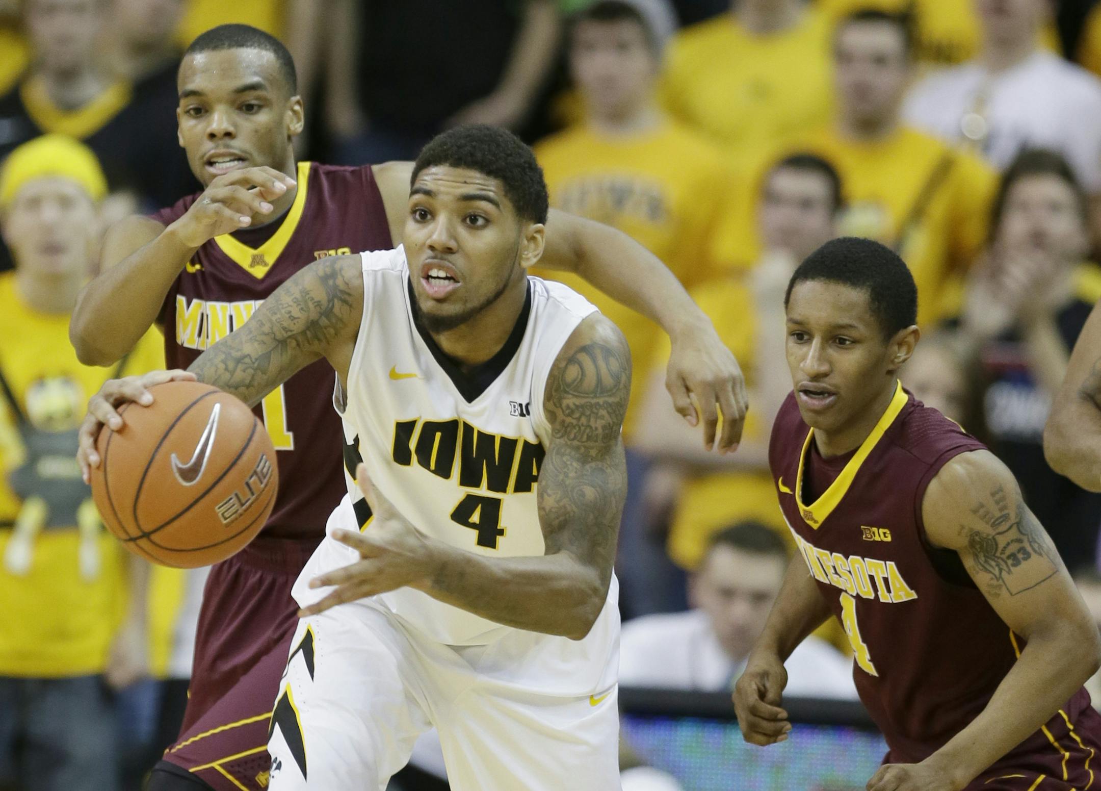Iowa guard Devyn Marble, center, drove up the court ahead of the Gophers' Andre Hollins, left, and Deandre Mathieu during the second half Sunday.