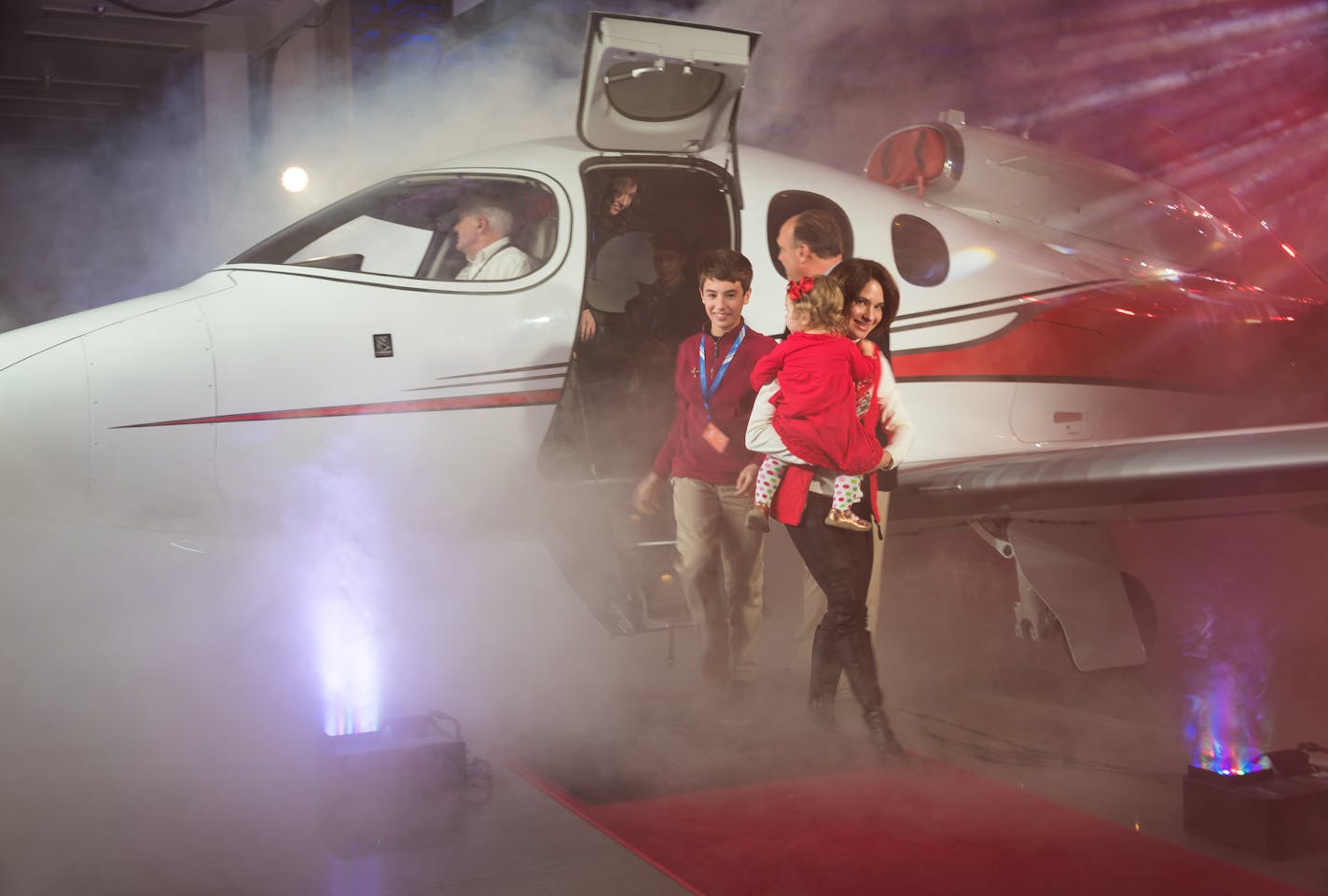 Cirrus Aircraft Vision Jet customer #1 Joe Whisenhunt escorts his family off their brand new aircraft -- the world's first single engine "Personal Jet" -- at Monday's celebration at the new Duluth Vision Jet Finishing Facility. Pictured is wife Connie, baby Eleanor and son Zeke. Credit: Mike Young