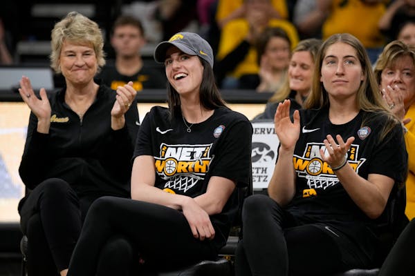 Iowa guard Caitlin Clark, center, sits with coach Lisa Bluder, left, and guard Kate Martin, right, during a team celebration Wednesday as she finds ou