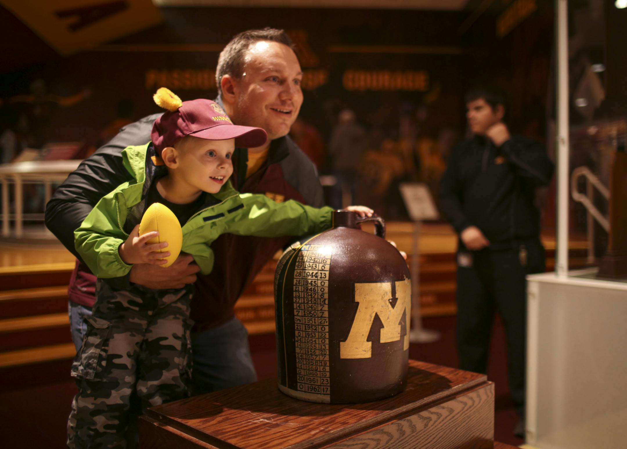 Rick Ostby of St. Louis Park posed for a photo with his son, Alex, 3, and the Little Brown Jug at TCF Bank Stadium Wednesday afternoon. ] JEFF WHEELER ‚Ä¢ jeff.wheeler@startribune.com U of M football fans were given an opportunity to view an artifact they haven't seen in a long time - the Little Brown Jug - the trophy traded back and forth between the University of Minnesota and the University of Michigan since 1903. The trophy was on display in the T. Denny Sanford Hall of Fame