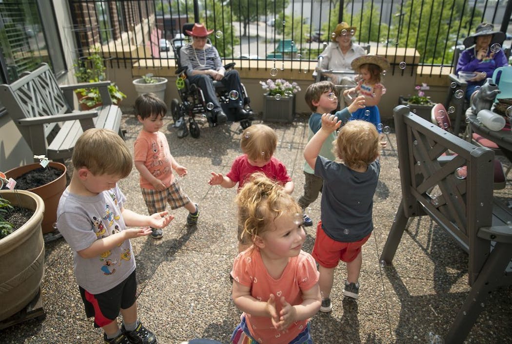 Children from the TowerLight Child Care Center played with bubbles as TowerLight Memory Care Unit residents watched after they watered plants as part of their multigenerational program.