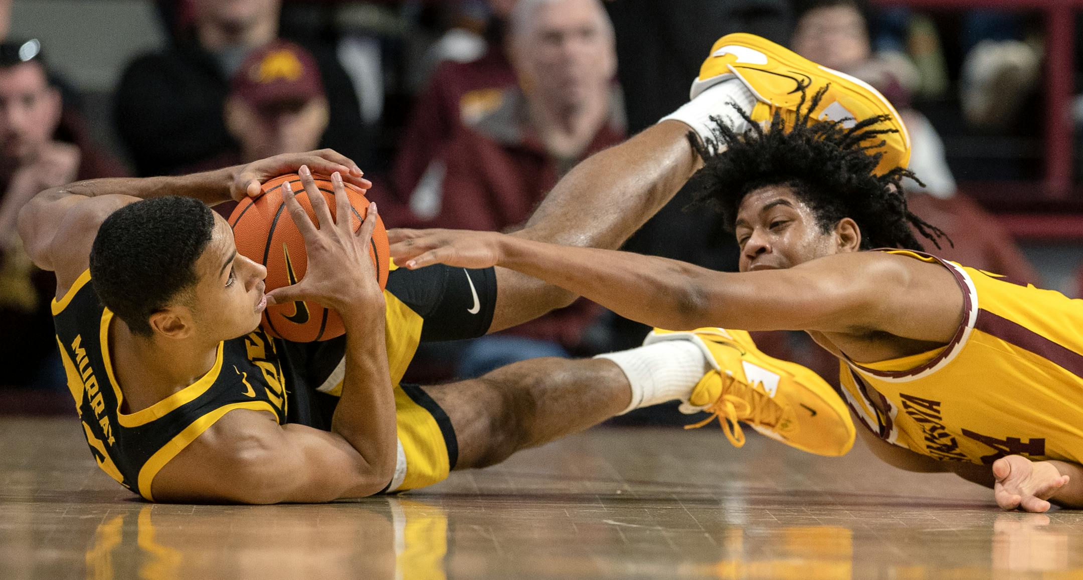 Kris Murray (24) of the Iowa Hawkeyes and Jaden Henley (24) of the Minnesota Gophers fight for a loose ball in the first half.