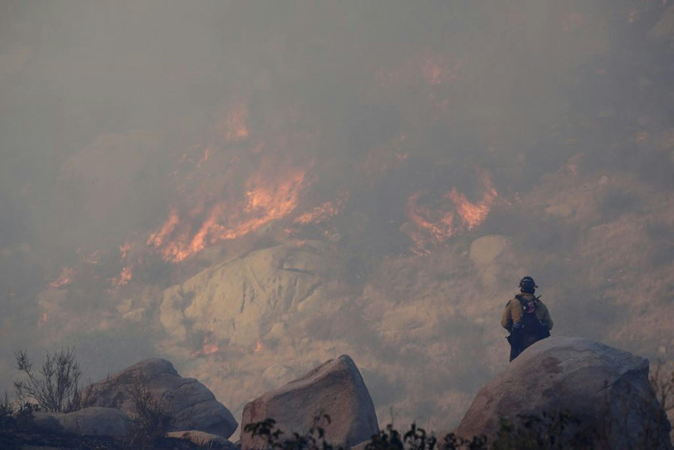 A firefighter watches a backfire burn while battling a wildfire, Thursday, Aug. 8, 2013, in Banning, Calif.