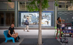 Daniel Brody listened as Debbie Moore played her violin near the Mary Tyler Moore statue on Nicollet Mall in downtown Minneapolis on June 13, 2023.