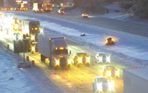 A traffic cam view of a car on the side of snow-covered roads.