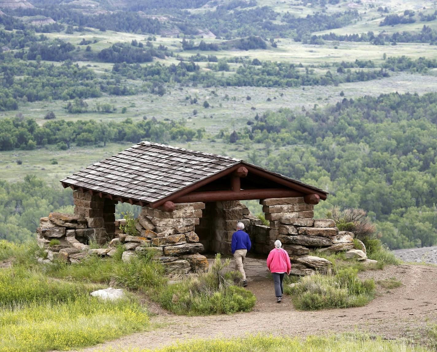 FILE--In this Wednesday, June 11, 2014, file photo, James Lyons and Florence Reaves, from Kirkwood, Mo., hike to a stone lookout over the Little Missouri River inside the Theodore Roosevelt National Park, located in the Badlands of North Dakota. Parties involved in a dispute over whether North Dakota regulators should be involved in the siting of a controversial oil refinery near Theodore Roosevelt National Park are battling in state court. The dispute is over whether state regulators should hav