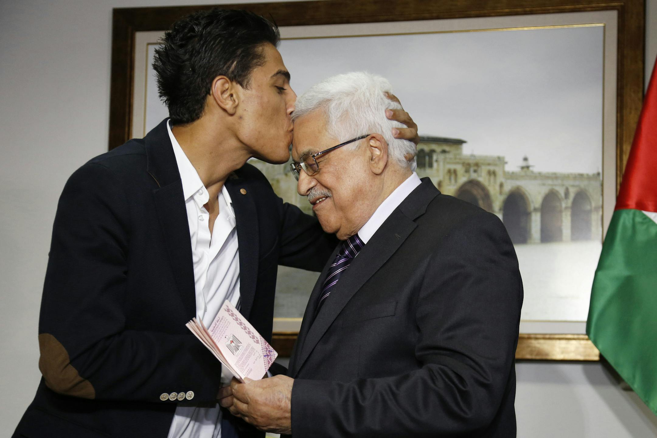 Arab Idol Mohammed Assaf, left, kisses Palestinian President Mahmoud Abbas as he hands him a diplomatic Palestinian Authority passport during their meeting in the West Bank city of Ramallah, Monday, July 1, 2013. Assaf, the 23-year-old from the Gaza Strip who won the popular pan-Arab song contest last month, met Abbas on Monday before performing in Ramallah. (AP Photo/Mohamad Torokman, Pool)