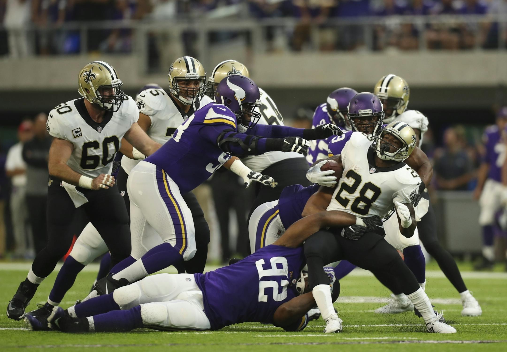 New Orleans Saints running back Adrian Peterson (28) was tackled by Minnesota Vikings defensive tackle Tom Johnson (92) after a first quarter run.