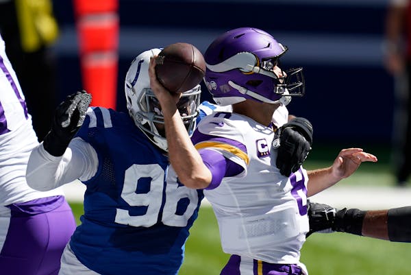 Minnesota Vikings quarterback Kirk Cousins, right, is pressured by dIndianapolis Colts' Denico Autry (96) during the first half of an NFL football gam