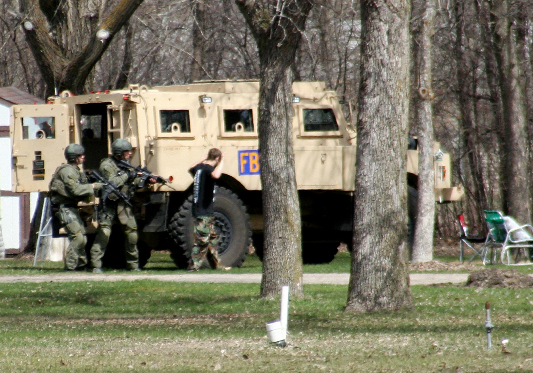 This May 3, 2013, photo provided by Jeremy Jones shows authorities with Buford Rogers, right, during a raid on a mobile home in Montevideo, Minn. Authorities said Monday, May 6, that Rogers was arrested, charged with one count of being a felon in possession of a firearm, and that the agency believes is disrupted a potential terror attack after a search of the home turned up Molotov cocktails, suspected pipe bombs and firearms.