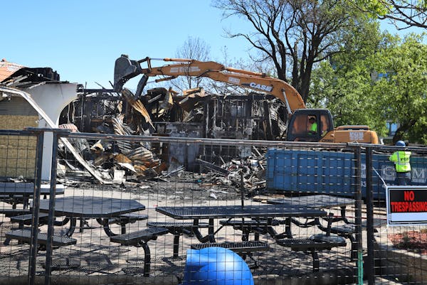 An excavator tears down the remnants of Lola on the Lake at the pavilion at Bde Maka Ska/Lake Calhoun, damaged beyond repair during a recent fire and 