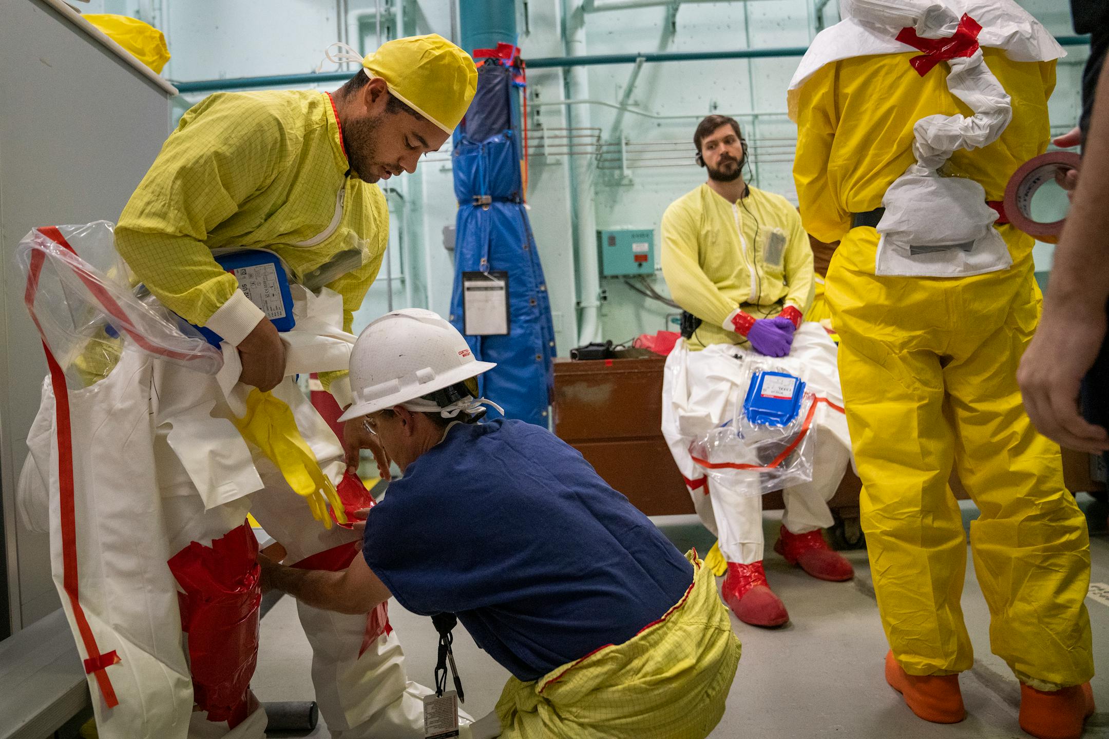 Nigel Hester, left, an under-vessel technician, gets help from fellow under-vessel technician Gary Sutton in suiting up before working on control rod drive replacement inside the reactor building.