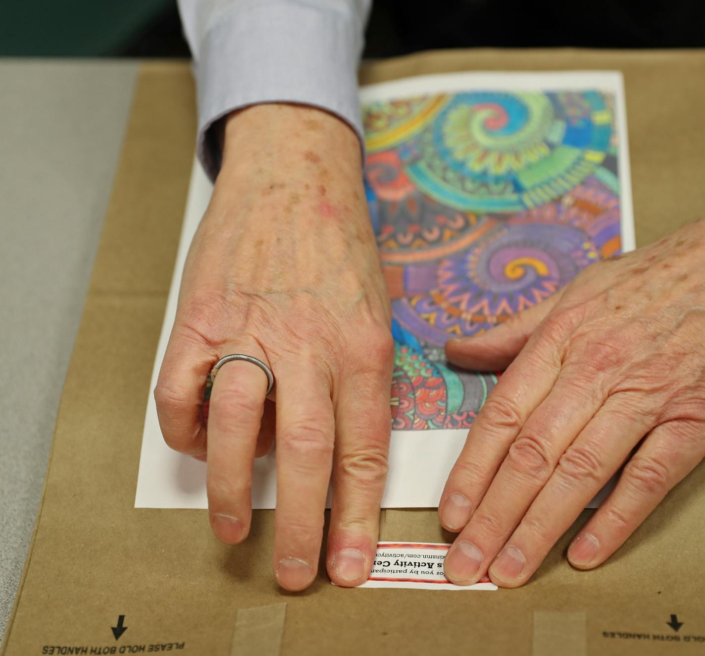 Robert Fisher shared his art-in-progress before he carefully placed a label on the finished product. The paper bags will be delivered to a thrift shop and food bank.