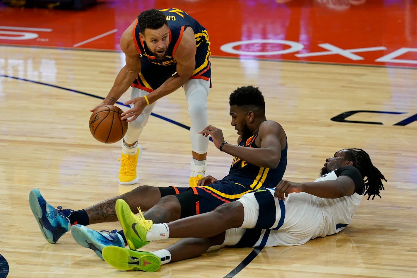 Golden State Warriors guard Stephen Curry, top, grabs the ball over forward Kevon Looney, middle, and Minnesota Timberwolves center Naz Reid during the second half of an NBA basketball game in San Francisco, Monday, Jan. 25, 2021. (AP Photo/Jeff Chiu)