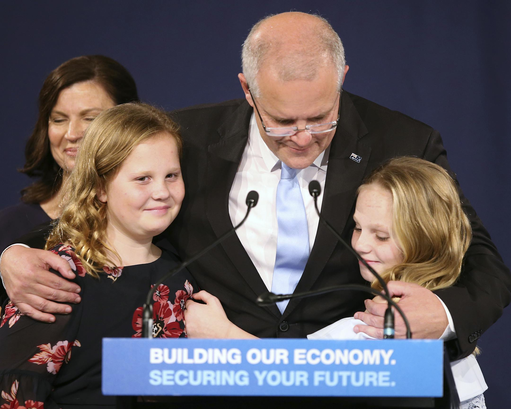 Australian Prime Minister Scott Morrison, center, embraces his daughters Lily, right, and Abbey, after his opponent concedes defeat in the federal election in Sydney, Australia, Sunday, May 19, 2019. Australia's ruling conservative coalition, lead by Morrison, won a surprise victory in the country's general election, defying opinion polls that had tipped the center-left opposition party to oust it from power and promising an end to the revolving door of national leaders. (AP Photo/Rick Rycroft)