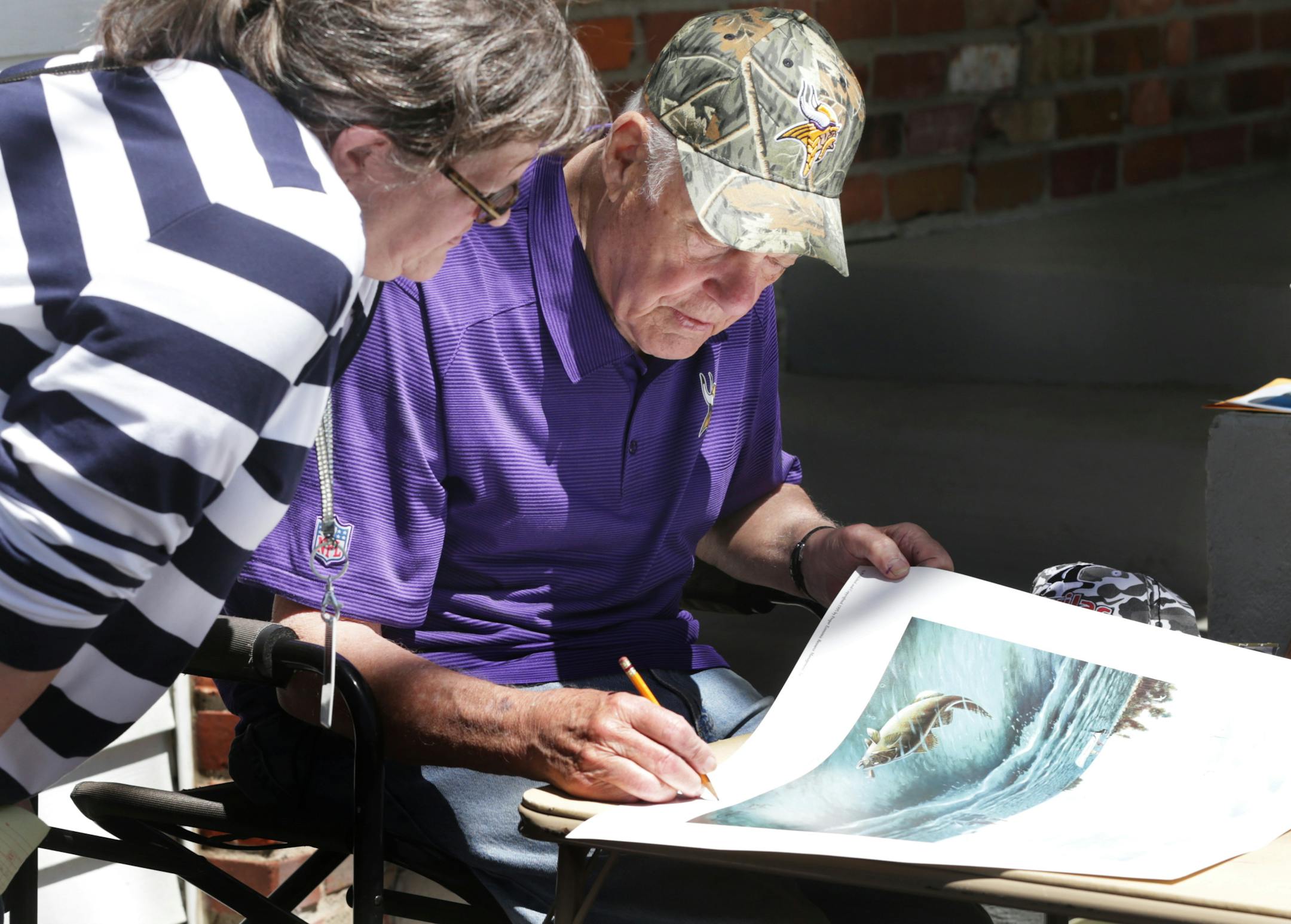 Former Minnesota Vikings head football coach Bud Grant signs a poster during his three-day garage sale in 2014.