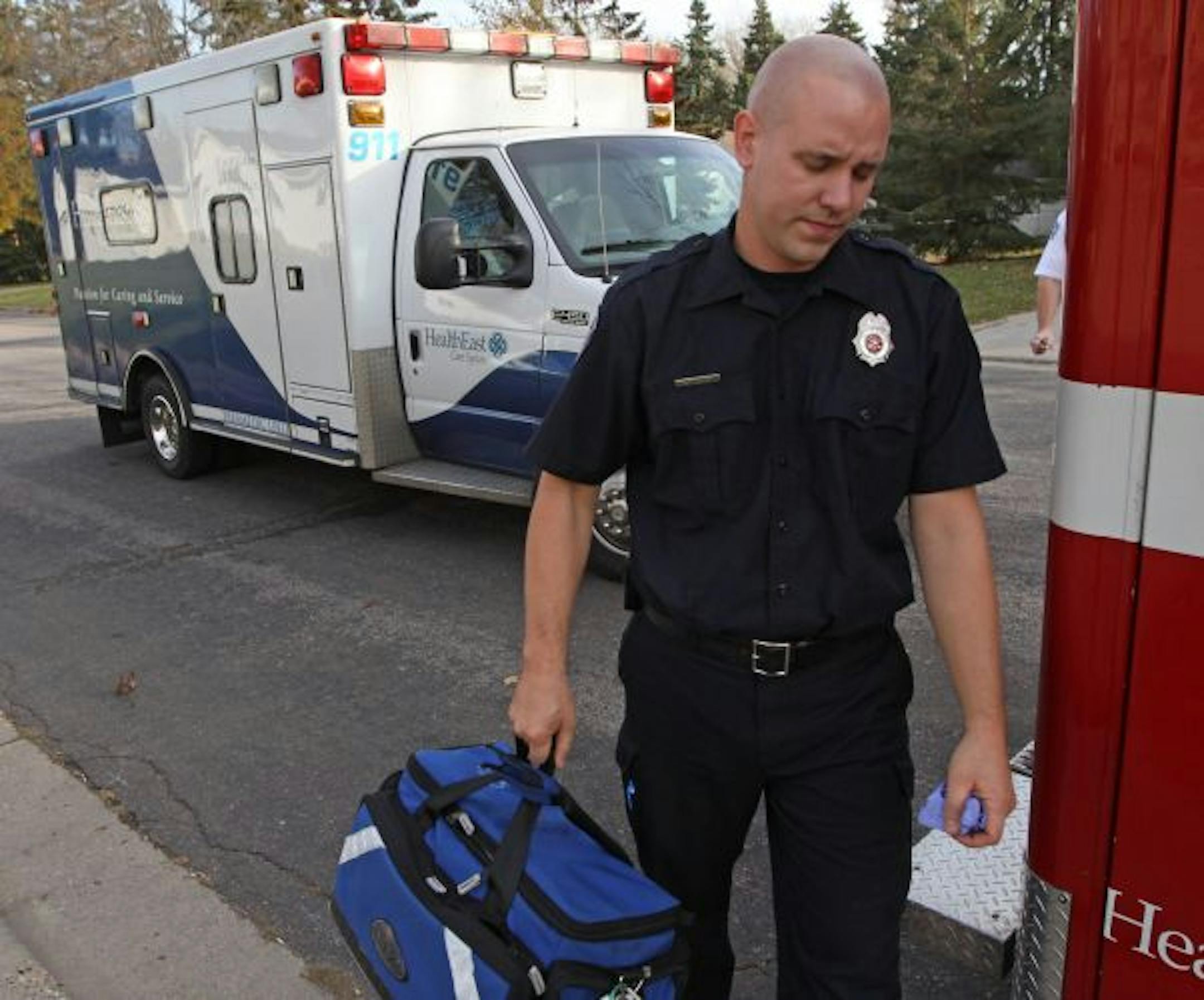 (center) South Metro Firefighter Sean Jansen collected his gear after responding to a medical emergency where a two year old girl had a seizure at her West St. Paul home. A HealthEast ambulance transported the girl.