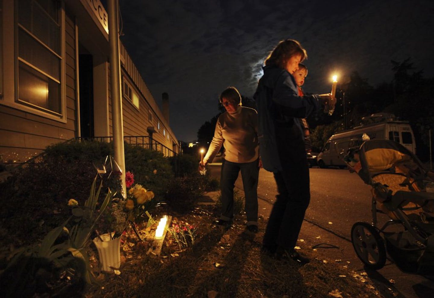 Dorothy Rice, left, who lives a few houses from the homicide scene, was joined by her daughter Cynthia Parson, right, and son Lakota, 1 1/2, outside Accents Signage Systems, Inc. Friday, Sept. 28, 2012, the day after scene of a multiple homicide in Minneapolis, Minn., where they added flowers to the makeshift Memorial outside the Minneapolis business. "As a child I played in the puddles outside this building," Parson said. "He was such a kind man," she said, referring to owner Reuven Rahamim, wh