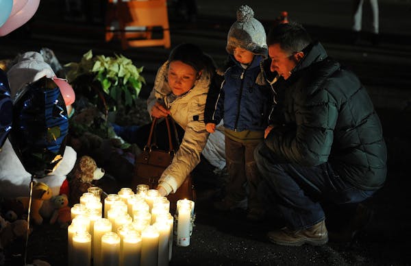 Candles are lit at a memorial near Sandy Hook Elementary School on Saturday, December 15, 2012 in Newtown, Connecticut, a day after a shooting rampage