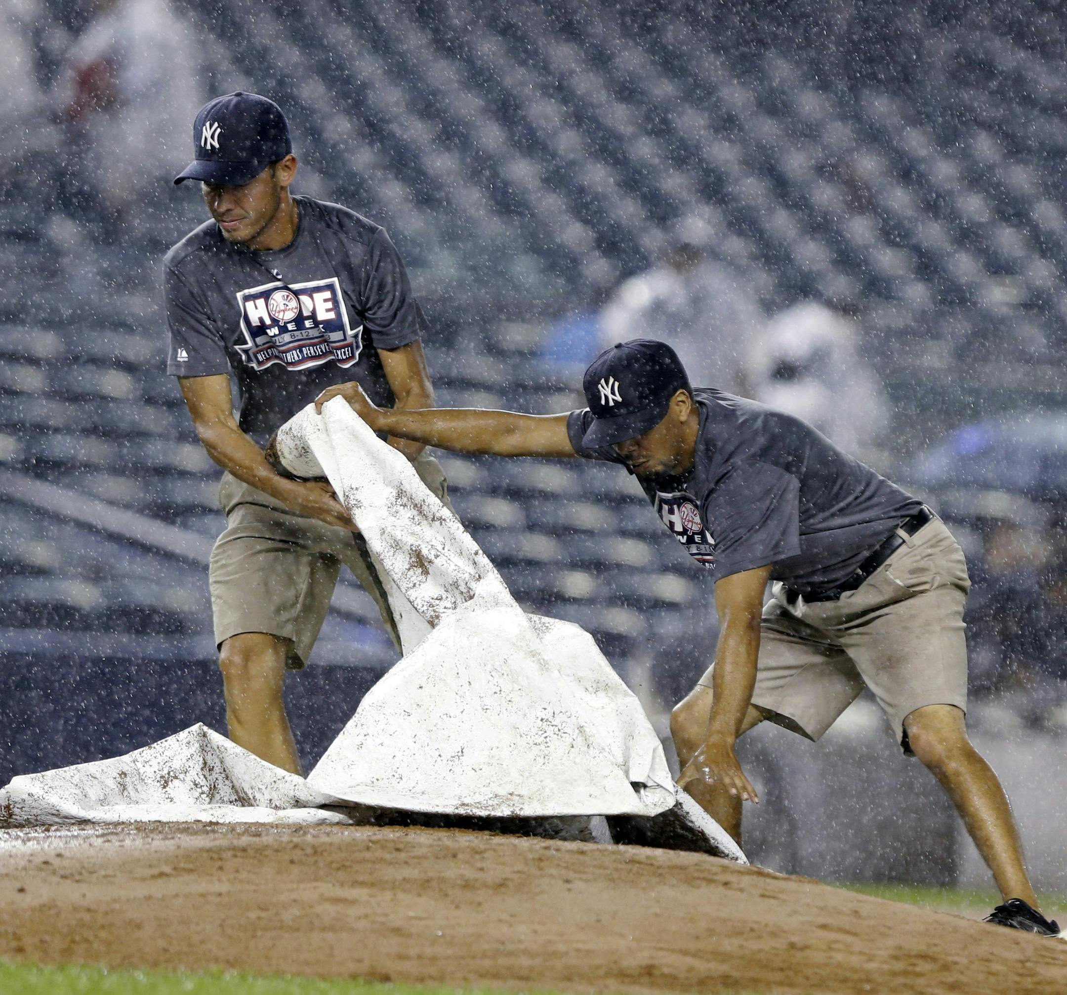 Members of the grounds crew cover the pitcher's mound during a rain delay in a baseball game between the Minnesota Twins and the New York Yankees on Friday, July 12, 2013, in New York. (AP Photo/Frank Franklin II)