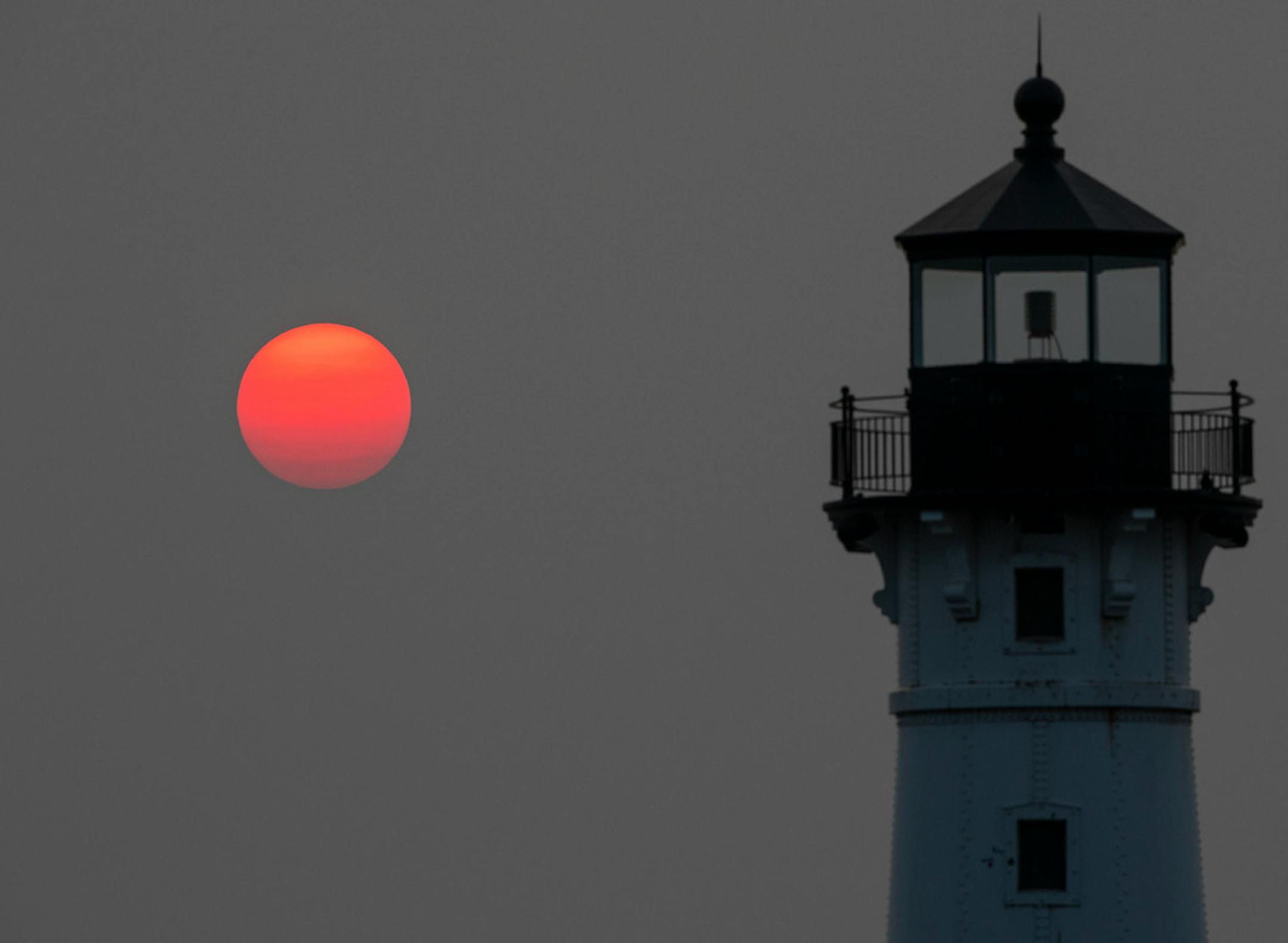 The sun rose over the Duluth Harbor North Breakwater Light on Monday, July 12, 2021. Canadian wildfires have caused smoke to drift in the atmosphere and blanket the Midwest skies with haze this past weekend. This has caused magnificent red sunrises over the last few mornings. ]
