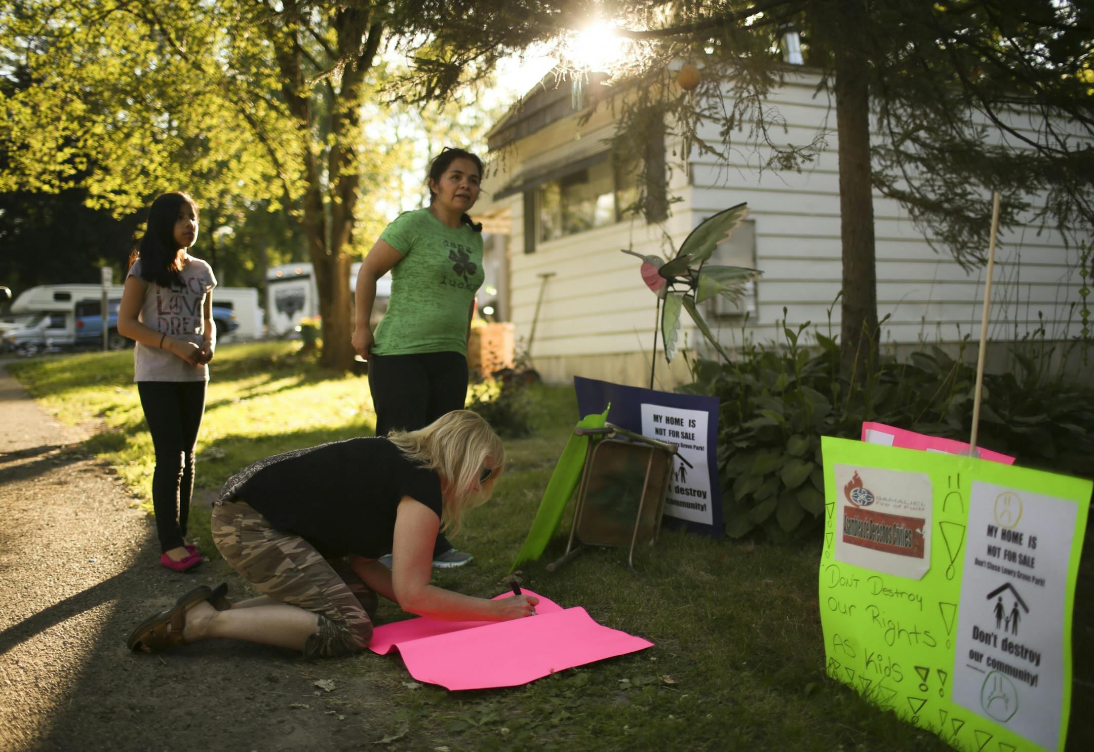 Antonia Alvarez stood with Luann Zappa while she made another sign for the Lowry Grove tenants group Thursday evening. At left was Alvarez's daughter, Melina Tapia. Alvarez led effort by tenants to buy the land their homes are on.