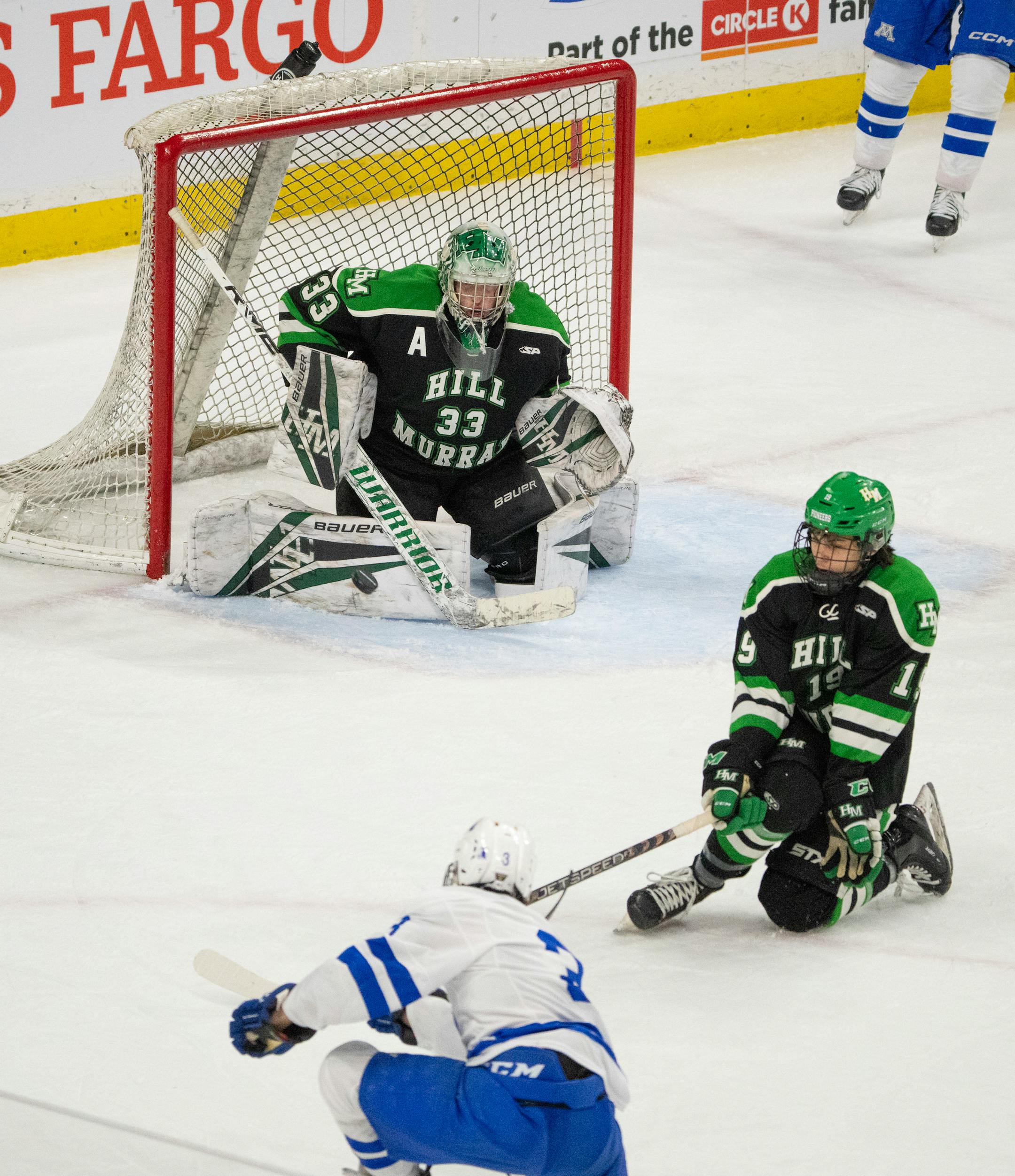 Hill-Murray Pioneers goaltender Jack Erickson (33) made a leg pad save of a shot by Minnetonka Skippers defenseman Daniel Klaers (3) in the third period while Hill-Murray Pioneers defenseman Graham Greeder (19) tried to block it.