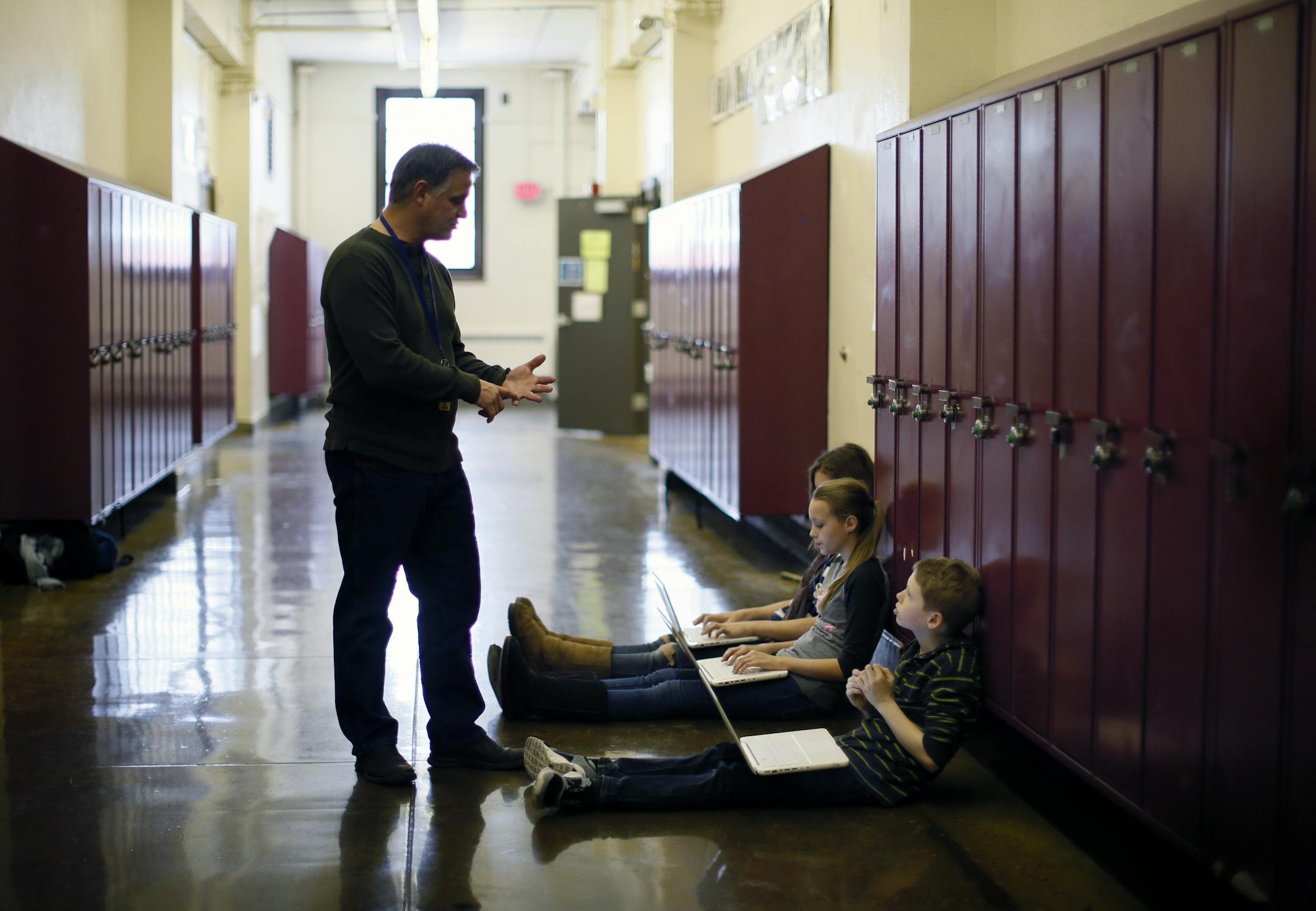 History teacher Eric Sparks works with 7th grade students, Lilah Schulz, Lydia Larson and Walker Ferguson in the hallway at Sanford Middle School. Sparks has a flexible classroom, allowing some students to work in the hallway during class.