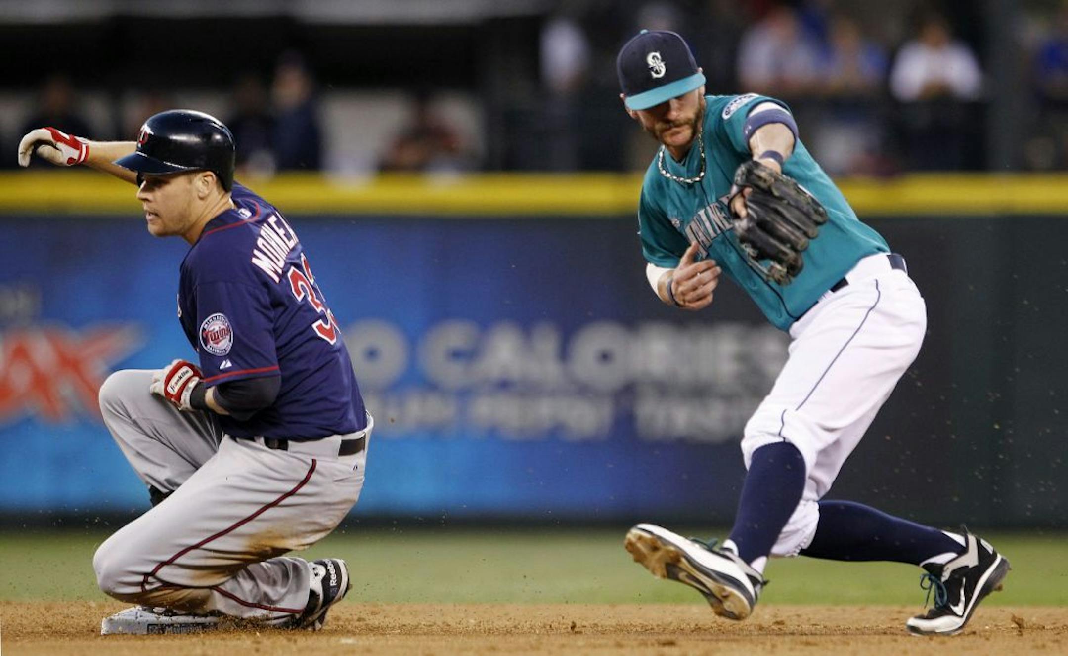 Seattle Mariners shortstop Brendan Ryan, right, snags a throw as Minnesota Twins' Justin Morneau slides safely into third in the fifth inning of a baseball game, Friday, Aug. 17, 2012, in Seattle.