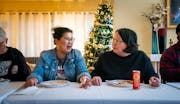 Kaohly Her, left, and Bo Thao-Urabe chatted at the dinner table duirng their giving circle’s year-end potluck.