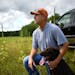 John Newpower, with Pheasants Forever, knelt down next to his 3-year old chocolate lab, Kiya while being interviewed Thursday on land purchased by Phe