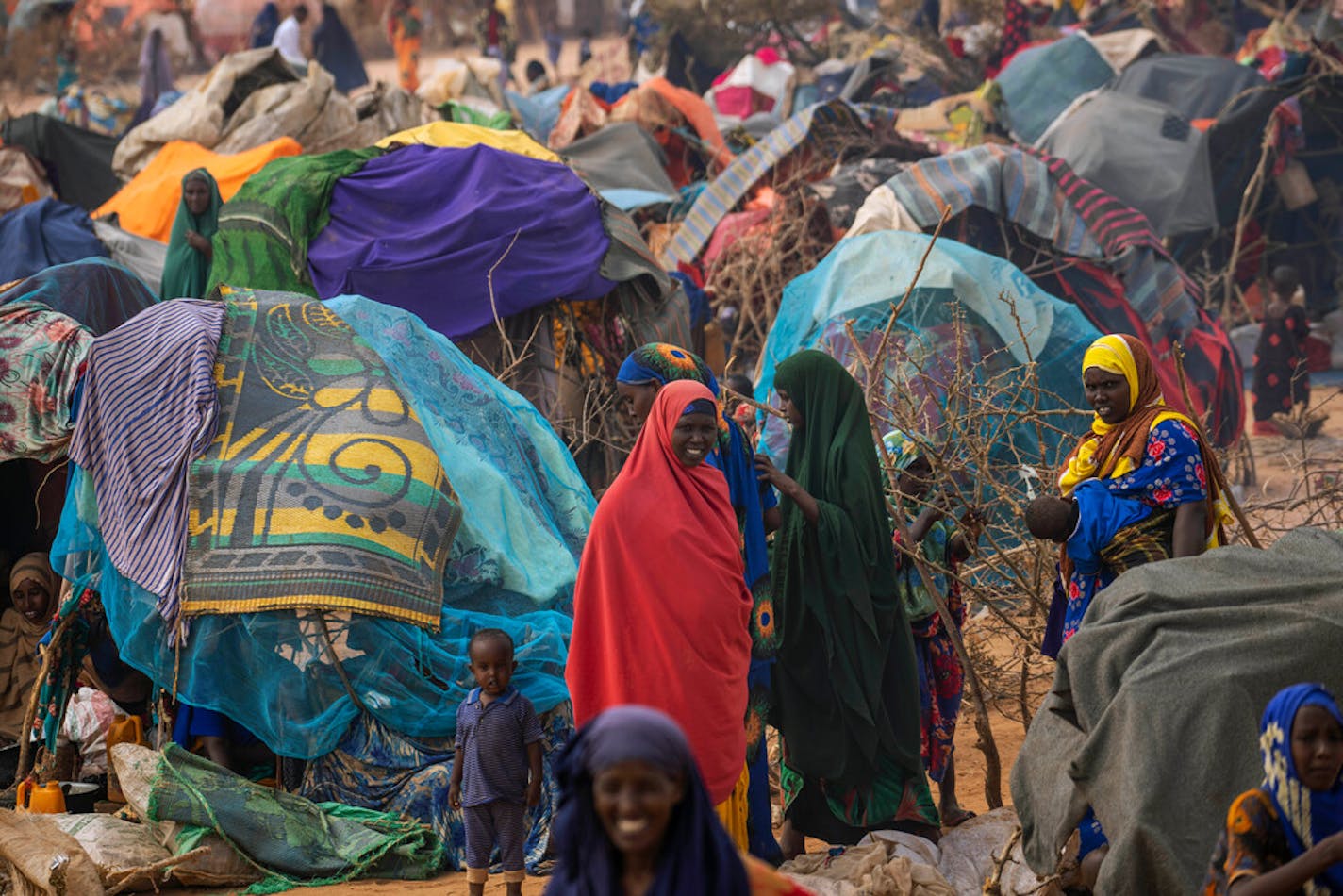 People walk through a displacement camp on the outskirts of Dollow, Somalia, on Sept. 19, 2022.