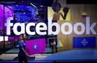 FILE - In this Tuesday, April 18, 2017, file photo, a conference worker passes a demo booth at Facebook's annual F8 developer conference, in San Jose,
