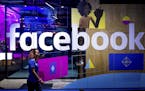 FILE - In this Tuesday, April 18, 2017, file photo, a conference worker passes a demo booth at Facebook's annual F8 developer conference, in San Jose,