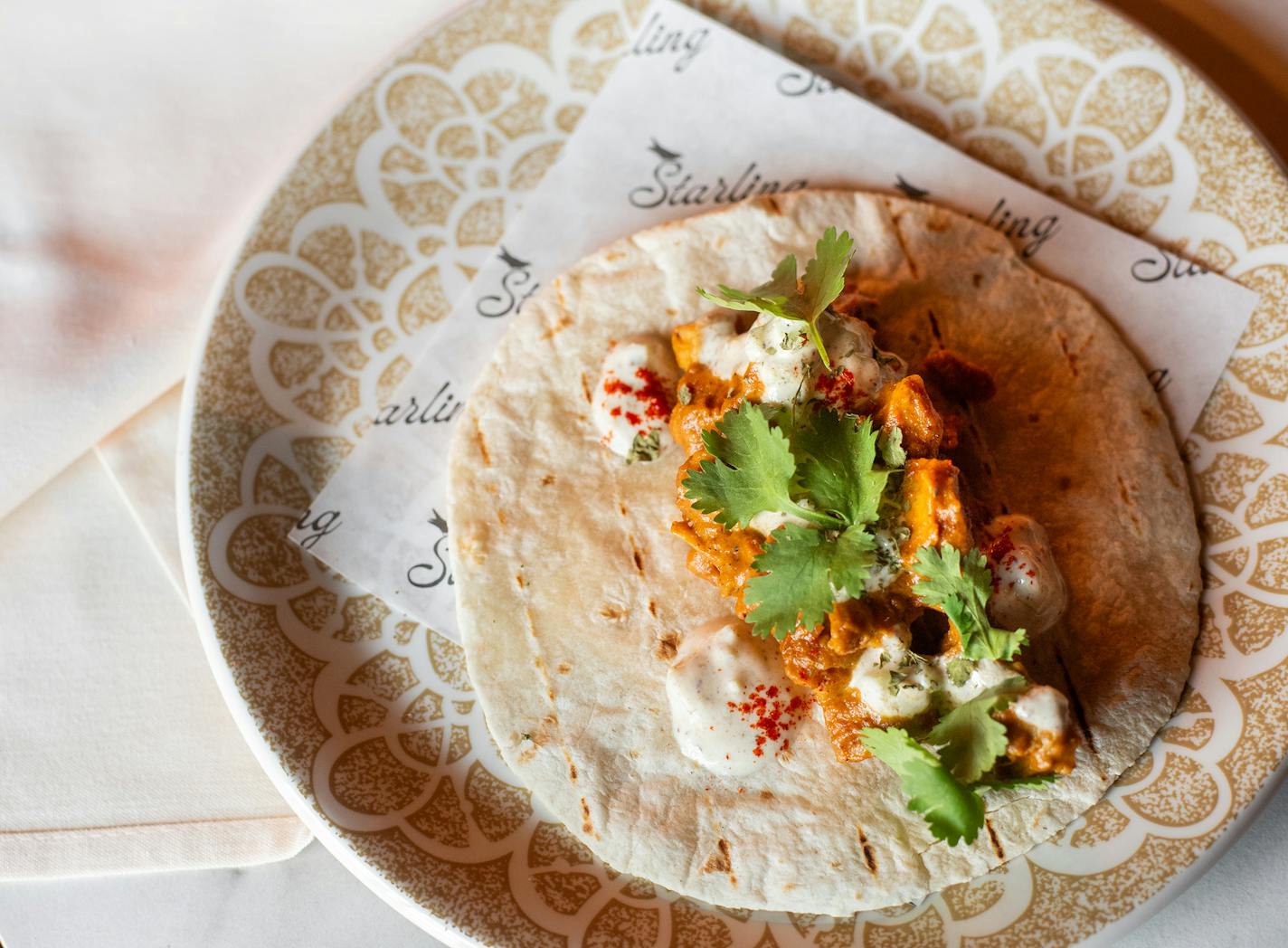 Delicious butter chicken taco on a plate with a napkin at the new Starling restaurant.