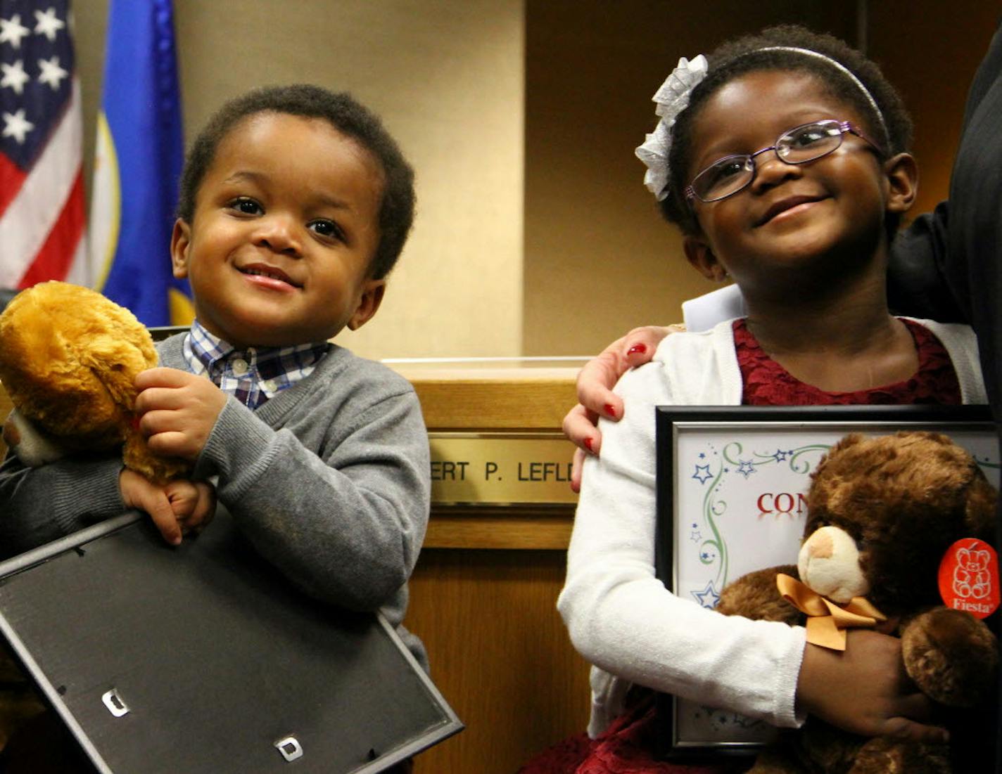 Brother and sister Damonte (left) and Mya smile as they hold the teddy bears and adoption certificates they received after a final hearing which legally allows them to join Allen and Lori Rausch as a family on Hennepin County's National Adoption Day on Nov. 21, 2015.