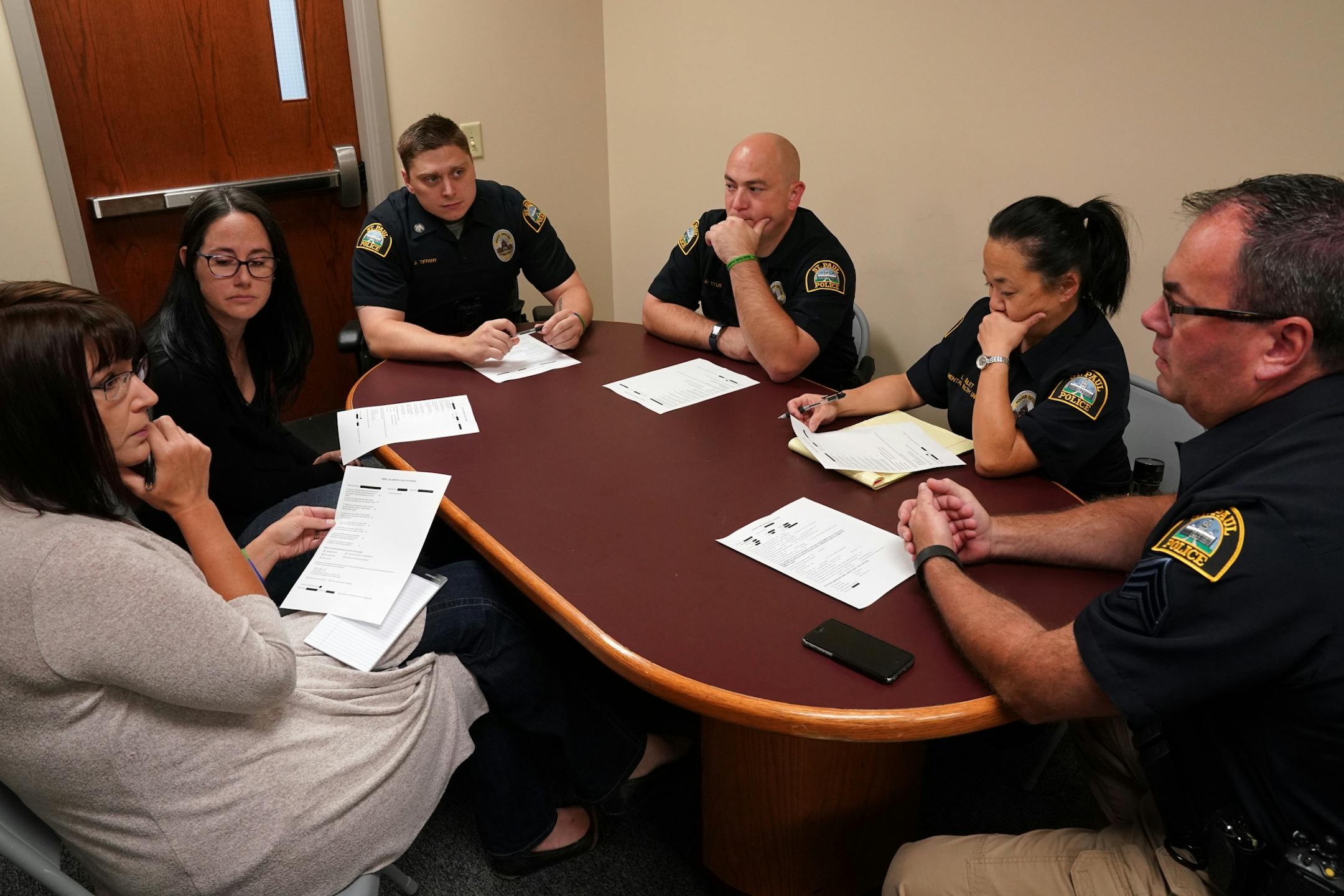 Sgt. Jamie Sipes, right, head of the St. Paul Police Department mental health unit held a meeting with his officers and the two social workers for Regions Hospital who are integrated into their unit. From left, licensed clinical social workers Amber Ruth and Kara Haroldson, officers Justin Tiffany, Marshall Titus and Lori Goulet.