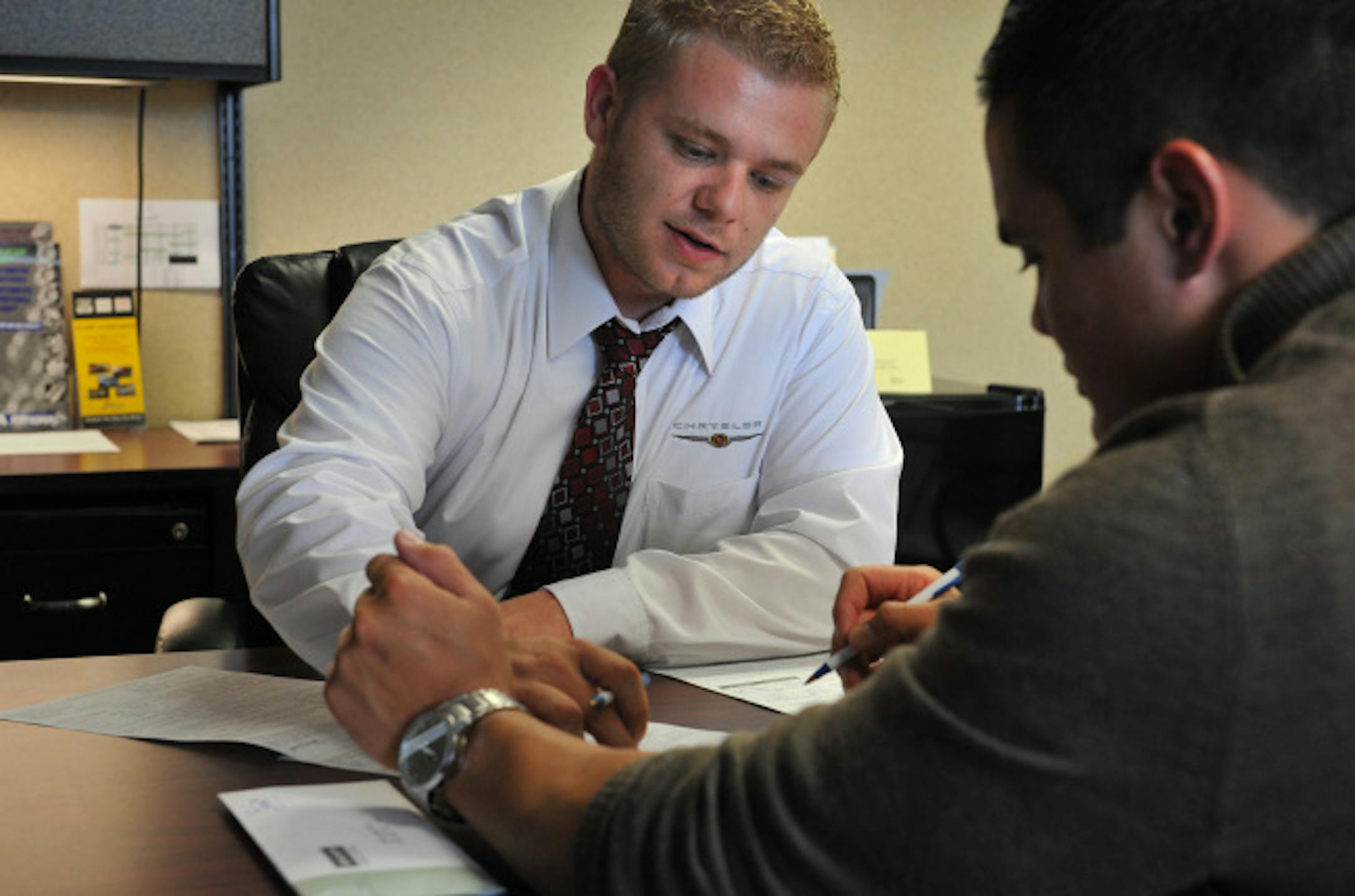 Patrick Hertel of Apple Valley, right, filled out loan paperwork on Wednesday at Walser Chrysler Jeep Dodge in Hopkins with Adam Kretch, Walser's finance director.