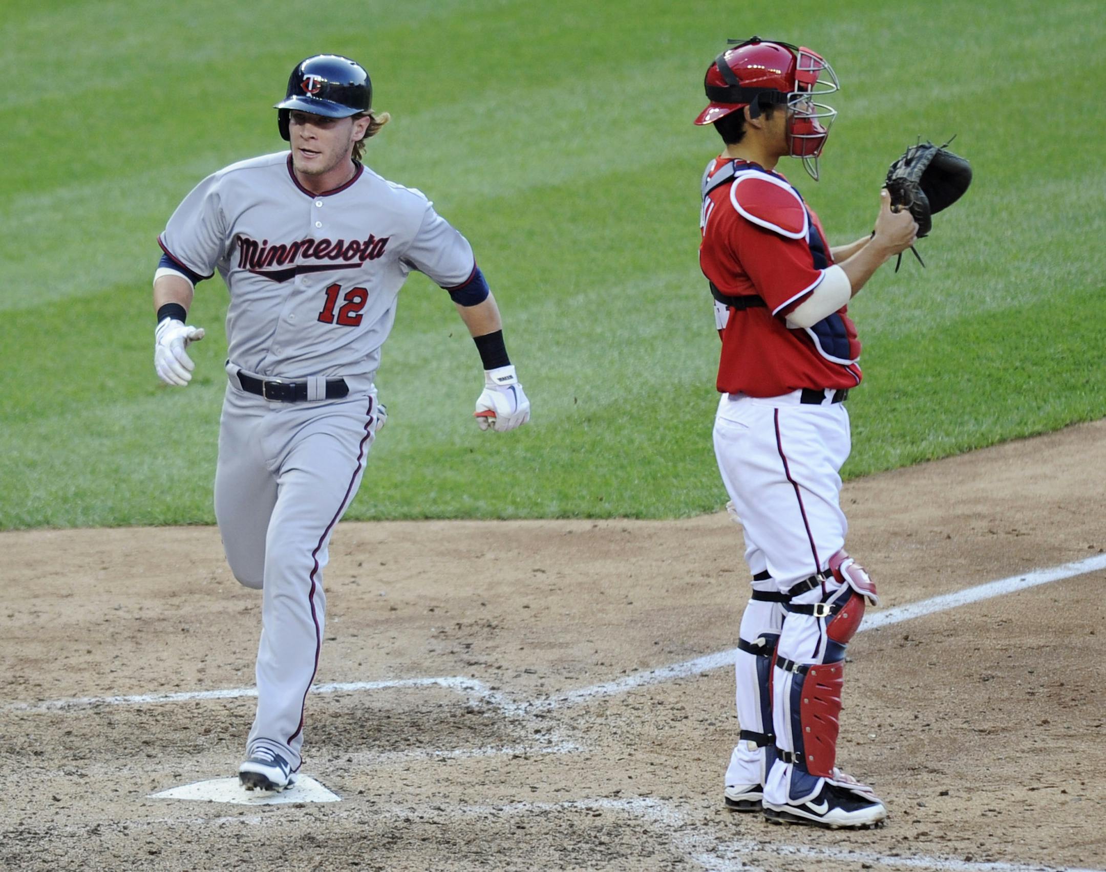 Minnesota Twins' Chris Herrmann (12) comes home to score the go-ahead run on a single by Ryan Doumit as Washington Nationals catcher Kurt Suzuki stands in front of the paly during the 11th inning of an interleague baseball game, Saturday, June 8, 2013, in Washington. At left is Twins' Josh Willingham. The Twins won 4-3 in 11 innings. (AP Photo/Nick Wass)