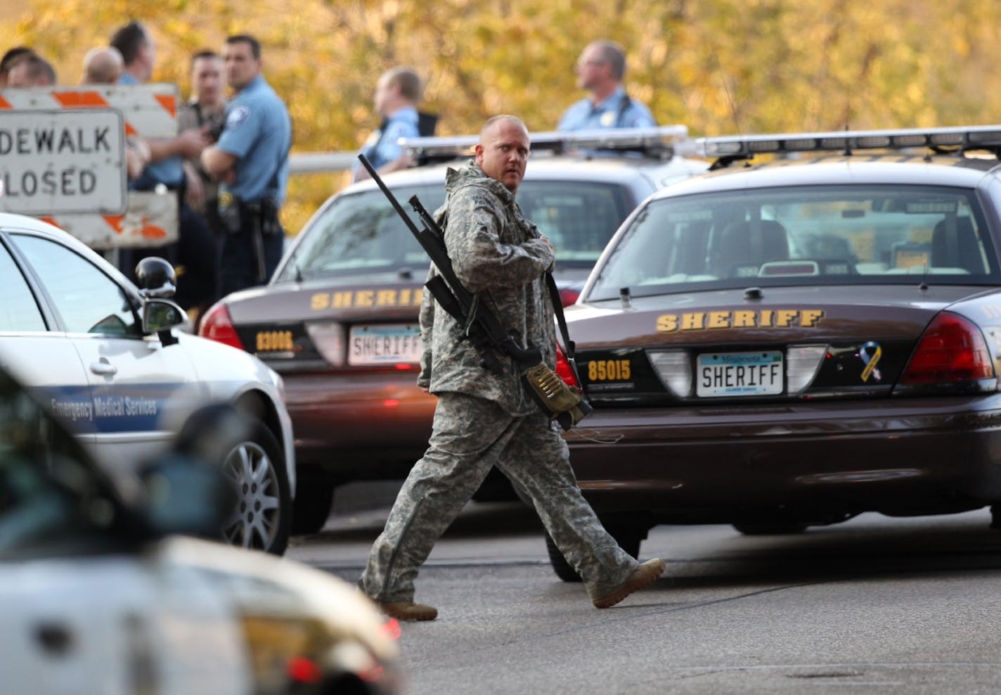 FILE - In this Sept. 27, 2012 file photo, an officer walks through the area as police investigate a shooting at Accent Signage Systems in Minneapolis. The family of Jacob Beneke, one of six people killed in the shooting, announced Friday, Feb. 1, 2013, they are suing the company and the attacker's estate claiming Accent Signage should have known that the attacker, Andrew Engeldinger, had violent tendencies, was mentally unstable and was a potential danger to others. (AP Photo/Star Tribune, Renee