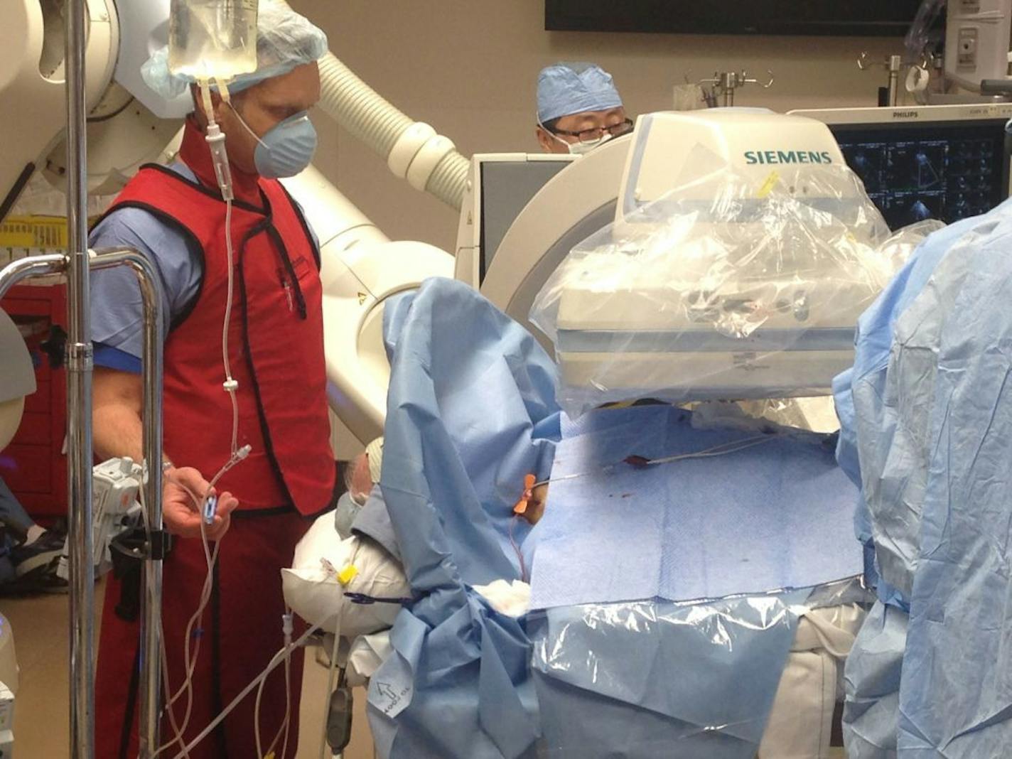 Anesthesiologist Tjorvi Perry (left) talks with patient Roy Nothnagel, who remained conscious during a procedure at Abbott Northwestern Hospital in Minneapolis last month to replace a defective heart valve. Conscious sedation is becoming more common in these procedures as research finds it improve outcomes and lowers costs.