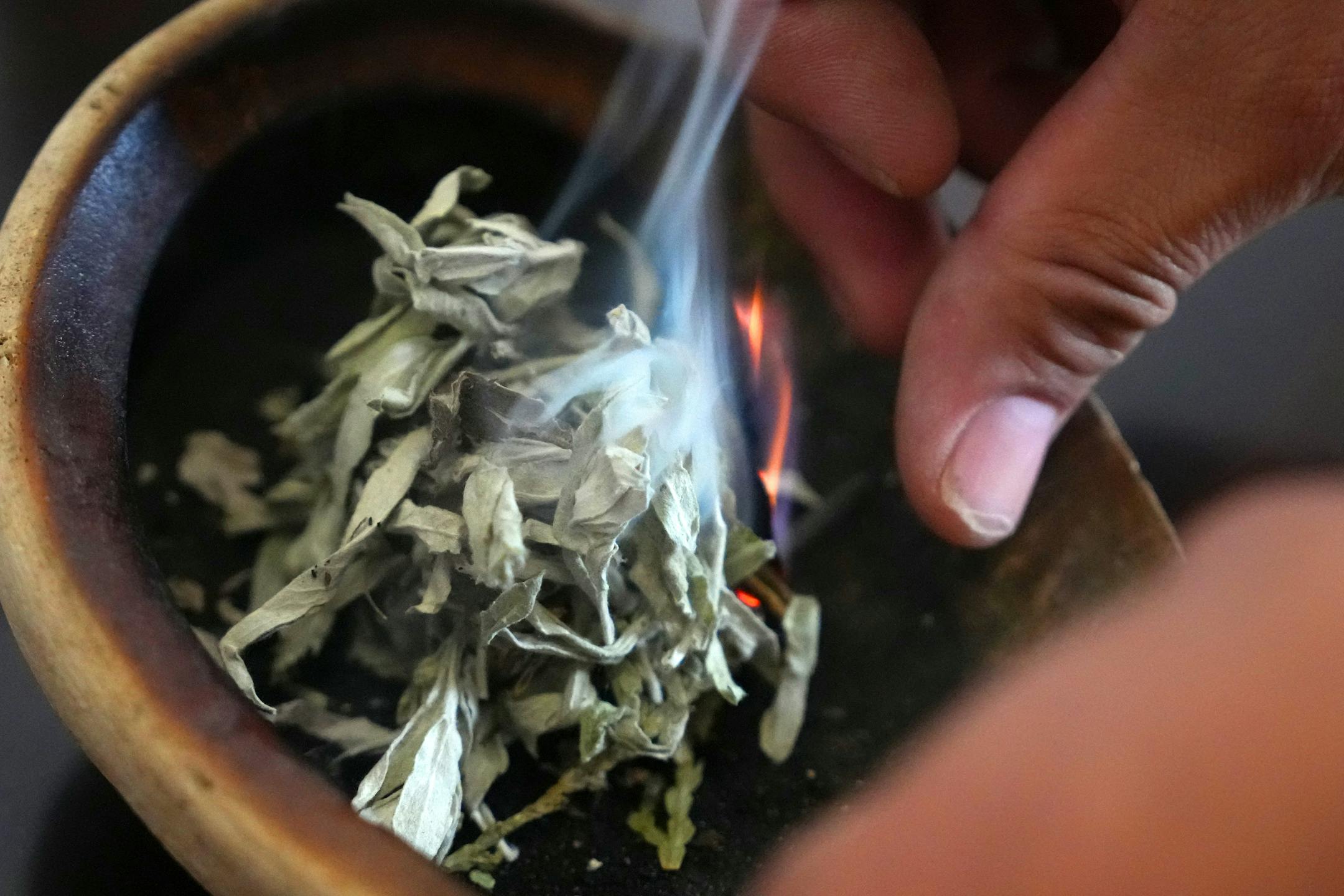 Thomas Draskovic, the kindergarten through fourth grade Lakota language and culture specialist at the American Indian Magnet School, lights a bundle of sage and cedar as he smudges the school on the first day of class in St. Paul.