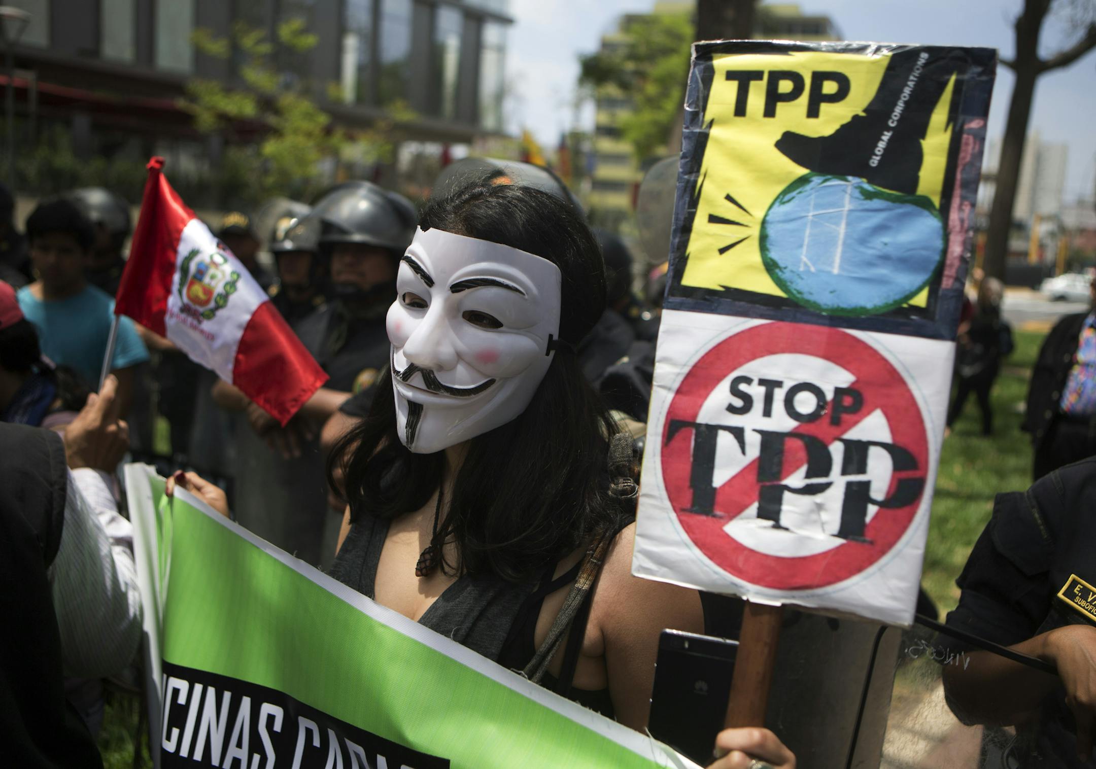 A protester holds signs against the Trans Pacific Partnership (TPP) during a rally in Lima, Peru, Friday, Nov. 18, 2016. As leaders of the Asia-Pacific Economic Cooperation (APEC) meet in Lima, dozens of people rallied against the TPP, a proposed trade agreement among twelve of the Pacific Rim countries, not including China. and the visit of U.S. President Barack Obama. (AP Photo/Esteban Felix)