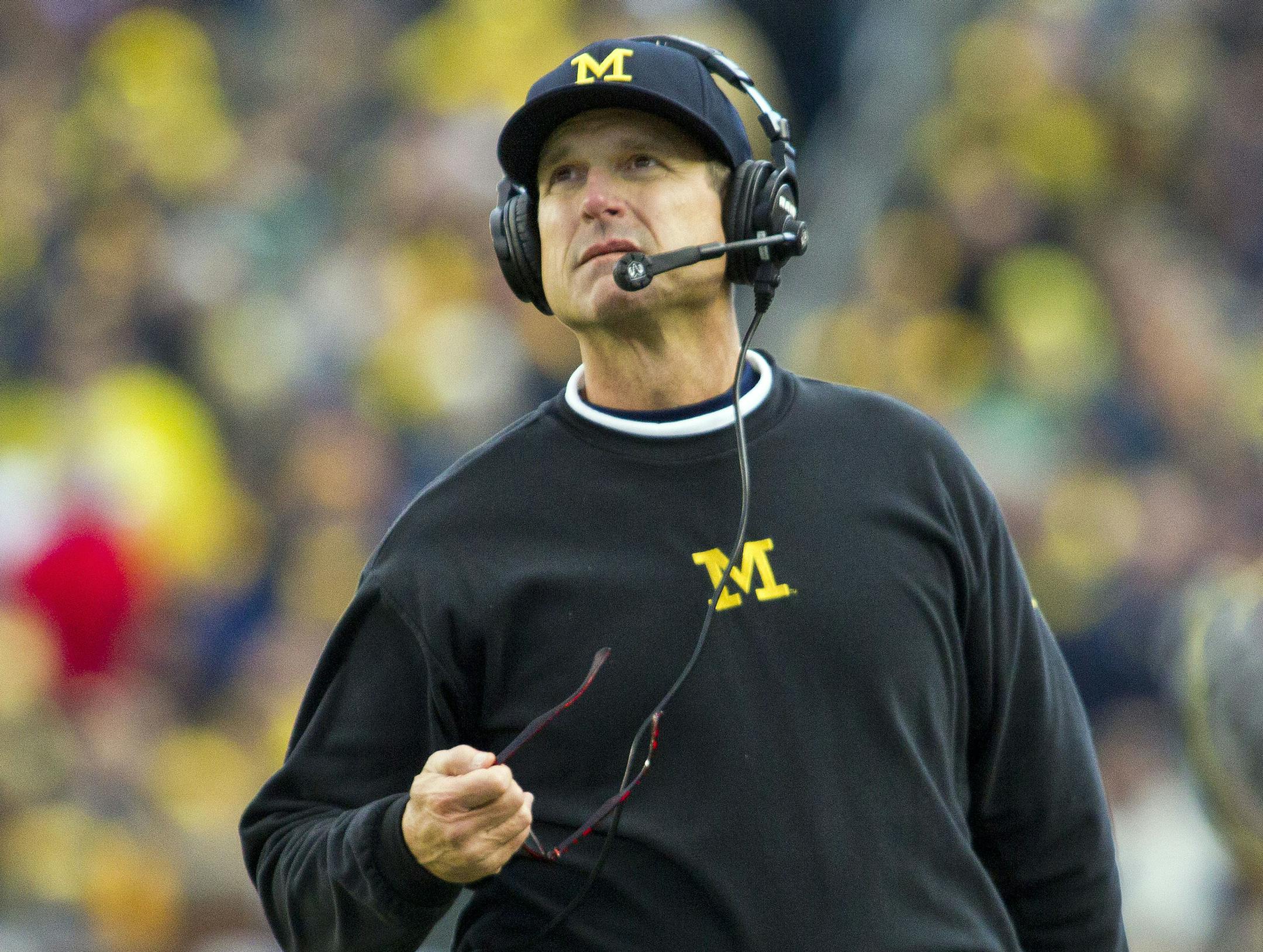 Michigan head coach Jim Harbaugh, wearing a headset, looks up at the scoreboard from the sideline in the third quarter of an NCAA college football game against Michigan State in Ann Arbor, Mich., Saturday, Oct. 17, 2015. Michigan State won 27-23. (AP Photo/Tony Ding)