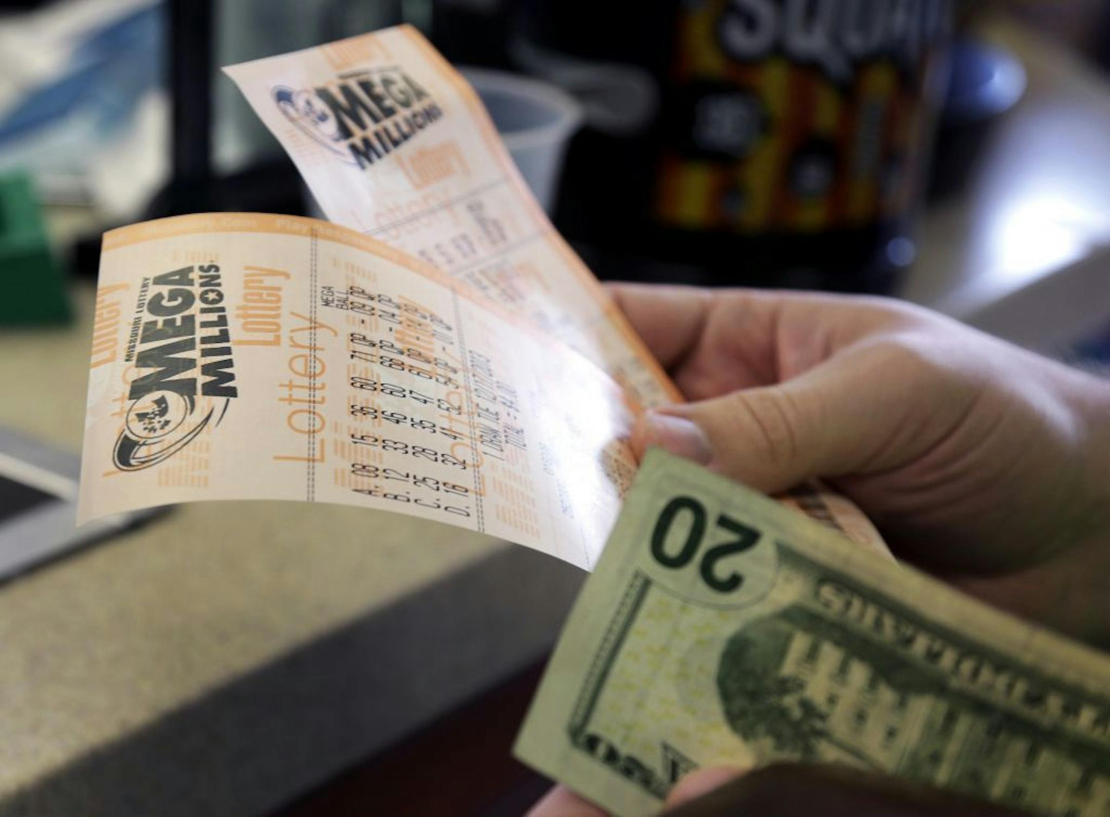 Scott Hoormann holds two Mega Millions lottery tickets he purchased at Energy Express Monday, Dec. 16, 2013, in St. Louis.