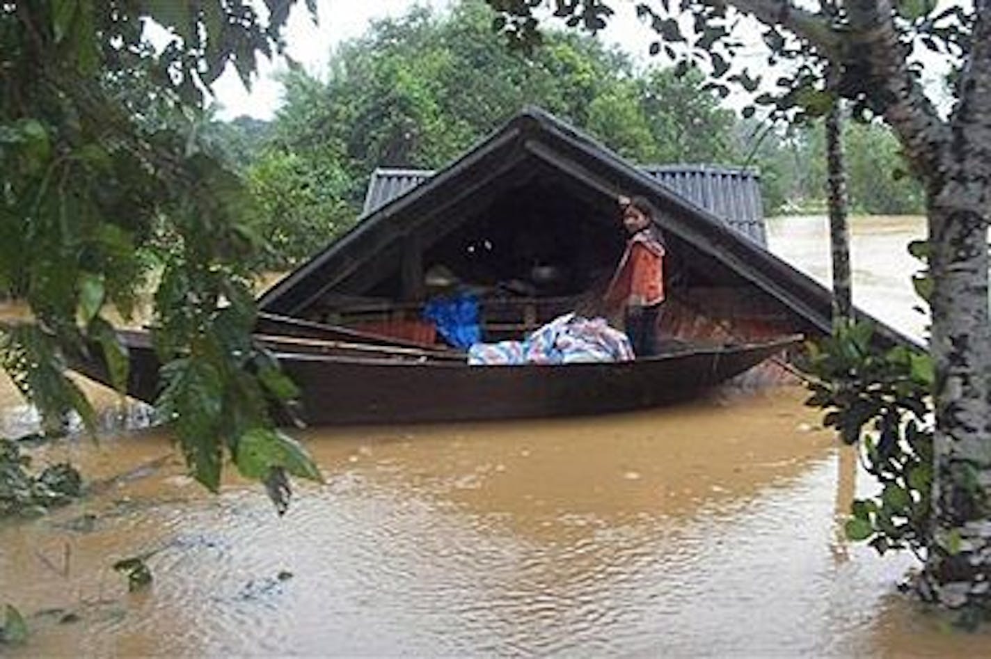 A girl stands on a boat in front of her flooded home in central Ha Tinh province Tuesday, Oct. 5, 2010. Central Vietnam braced for more rain Tuesday as the death toll from floods rose to 15 with ten others still missing, according to Vietnamese disaster officials and government. (AP Photo/VNA, Cong Tuong)