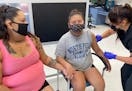 Summer Ariwite holds hands with her niece, Kaycee Moss, who recently turned 12, old enough to be vaccinated for COVID-19 by Samantha Allen, a public-h