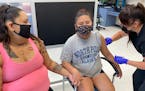Summer Ariwite holds hands with her niece, Kaycee Moss, who recently turned 12, old enough to be vaccinated for COVID-19 by Samantha Allen, a public-h