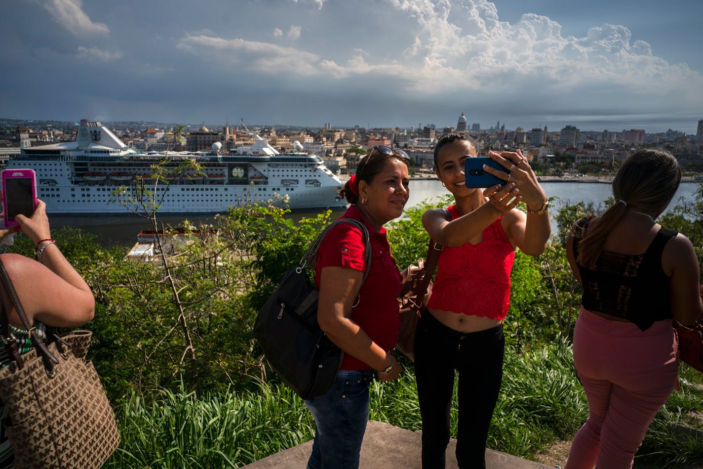 Women took a selfie with the Empress of the Seas, a Royal Caribbean vessel, in the background, leaving the harbor in Havana, Cuba, on Wednesday. Major cruise lines on Wednesday immediately began dropping stops in Cuba from their itineraries and hastily rerouting ships to other destinations including Mexico, in response to the Trump administration's new restrictions on travel to Cuba.