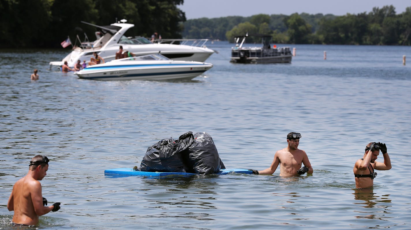 Volunteers collect trash as boaters relax and party behind them near Big Island on Lake Minnetonka. ] (Leila Navidi/Star Tribune) leila.navidi@startribune.com BACKGROUND INFORMATION: Clean up near Big Island on Lake Minnetonka on July 5, 2016. Volunteers are increasing clean-up efforts on Lake Minnetonka after the rowdy July 4th holiday weekend results in boatloads of trash. On Tuesday, Hennepin County Sheriff's Office divers will join the effort for the first time, diving for broken beer bottle